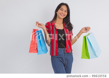 an asian woman standing with a lot of shopping bag at her hands an asian woman standing with a lot of shopping bag at her hands 99818558