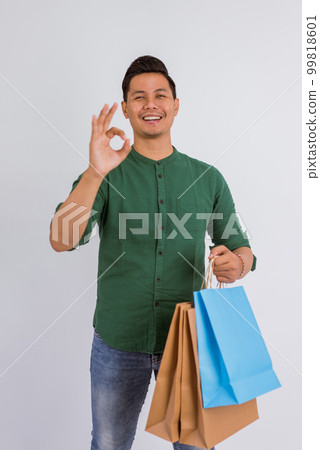 asian man standing with oke hand gesture while bring the shopping bags asian man standing with oke hand gesture while bring the shopping bags 99818601