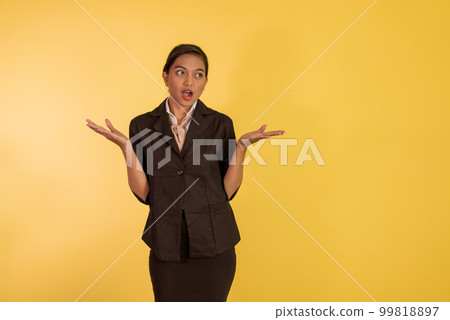 confused asian woman in formal outfit standing raising her hands 99818897