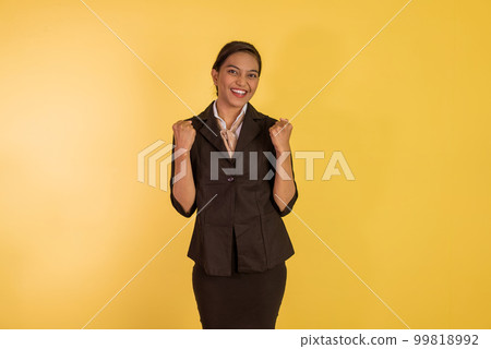 asian woman in formal outfit standing with clenched arms and smiling 99818992