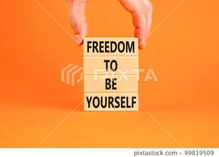 Freedom to be yourself symbol. Concept words Freedom to be yourself on wooden blocks on a beautiful orange background. Businessman hand. Business, psychological freedom to be yourself concept. 99819509
