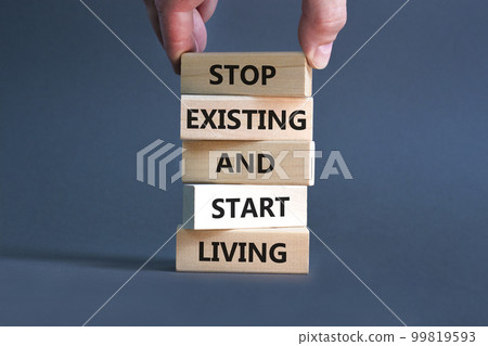 Stop existing start living symbol. Concept words Stop existing and start living on wooden blocks. Beautiful grey table grey background. Business Stop existing start living concept. Copy space. 99819593