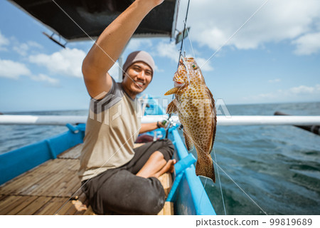 A grouper is hooked while fishing with a fishing rod 99819689