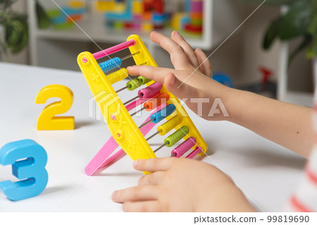 A small child learns to count on abacus, mathematics, arithmetic for children. 99819690