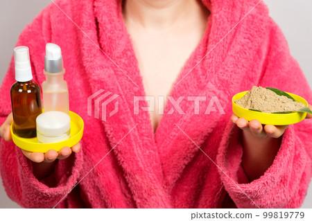 A woman in a pink bathrobe keeps cosmetics for skin care decollete 99819779