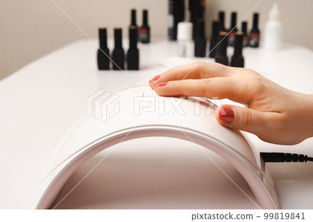 Led uv lamp for drying gel polish and hand with pink coating. Manicure, spa salon Led uv lamp for drying gel polish and hand with pink coating. Manicure, spa salon 99819841