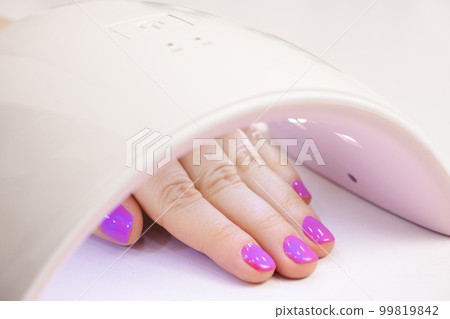 Drying the top for gel polish in an ultraviolet LED lamp. Manicure at home yourself, beauty salon Drying the top for gel polish in an ultraviolet LED lamp. Manicure at home yourself, beauty salon 99819842