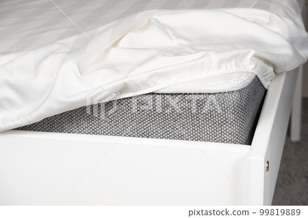 White satin sheet on an elastic band on the mattress. Bed linen on the bed 99819889
