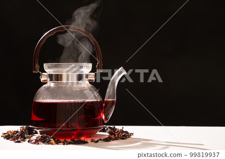 Red hibiscus tea from the petals of a Sudanese rose in a glass teapot, copy the place for the text Red hibiscus tea from the petals of a Sudanese rose in a glass teapot, copy the place for the text 99819937