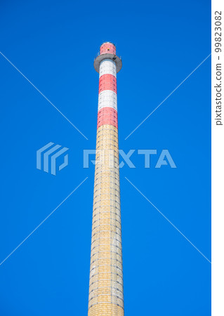 High industrial chimney rising up into clear blue sky 99823082