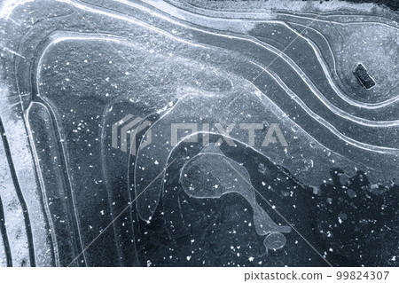 Textured ice background with white snow curves on the surface, and an air bulb in the shape of a whale. The photo showcases the beauty and intricacy of nature's designs in a winter landscape. High 99824307