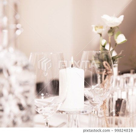 Festive decorated table in a restaurant, candle, wine glasses, vase, flowers on a white tablecloth. Restaurant, celebration, wedding Festive decorated table in a restaurant, candle, wine glasses, vase, flowers on a white tablecloth. Restaurant, celebration, wedding 99824819