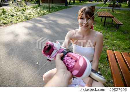 A smiling young person sits on a park bench. 99827093