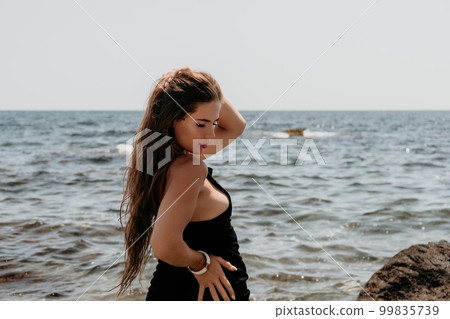Woman summer travel sea. Happy tourist in hat enjoy taking picture outdoors for memories. Woman traveler posing on the beach at sea surrounded by volcanic mountains, sharing travel adventure journey Woman summer travel sea. Happy tourist in hat enjoy taking picture outdoors for memories. Woman traveler posing on the beach at sea surrounded by volcanic mountains, sharing travel adventure journey 99835739