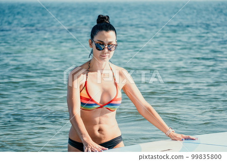 Sea woman sup. Silhouette of happy middle aged tanned woman in rainbow bikini, surfing on SUP board, confident paddling through water surface. Idyllic sunset. Active lifestyle at sea or river. Sea woman sup. Silhouette of happy middle aged tanned woman in rainbow bikini, surfing on SUP board, confident paddling through water surface. Idyllic sunset. Active lifestyle at sea or river. 99835800