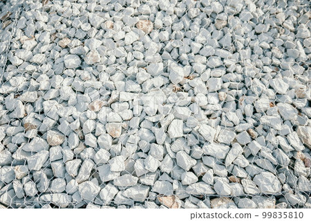 Granite stones behind a metal grate for strengthening the slope. Stones behind the wire. grey texture. construction. Granite stones behind a metal grate for strengthening the slope. Stones behind the wire. grey texture. construction. 99835810