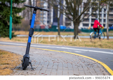 An electric scooter near the bike path. Close-up. Focus on the foreground 99835874