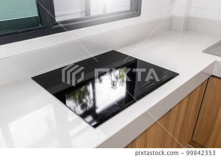 Black electric stove in a clean white kitchen 99842353
