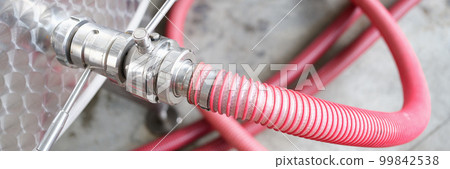 Red faucet connected to steel barrel in factory closeup Red faucet connected to steel barrel in factory closeup 99842538