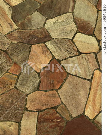 A vertical background image of a light ocher colored rough paving stone surface 99842610