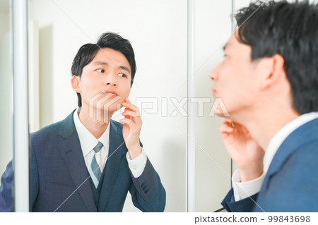 A young office worker who cares about rough skin in front of the mirror A young office worker who cares about rough skin in front of the mirror 99843698