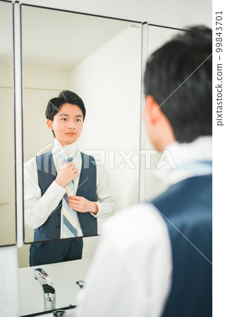 一個年輕的上班族在鏡子前收緊領帶 一個年輕的上班族在鏡子前收緊領帶 99843701