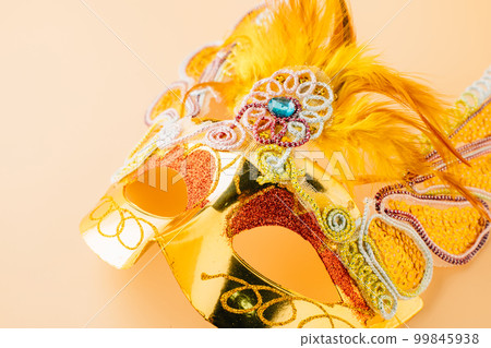 Happy Purim carnival decoration. Close up golden venetian ball mask isolated on pastel background, Jewish Purim or Mardi Gras in Hebrew, holiday background banner design, Masquerade party Happy Purim carnival decoration. Close up golden venetian ball mask isolated on pastel background, Jewish Purim or Mardi Gras in Hebrew, holiday background banner design, Masquerade party 99845938