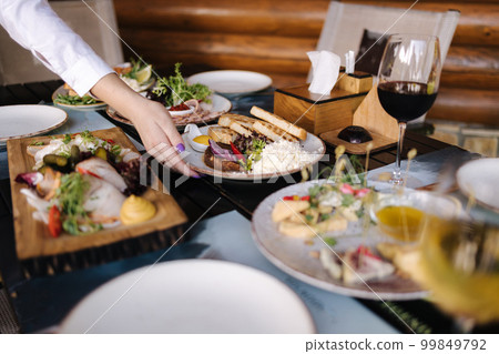 The waiter puts a plate with a snack on a table with food. Transcarpathian traditions Ukraine 99849792