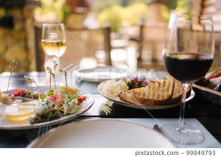 Salmon tartare served with grated butter and roasted bread. Glass of dry wine. Table with food on terrace 99849793
