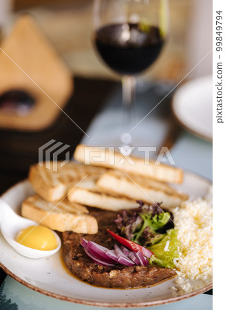 Beef tartar with grated butter and raw chicken yolk served with roasted bread. Glass of white and red wine Beef tartar with grated butter and raw chicken yolk served with roasted bread. Glass of white and red wine 99849794