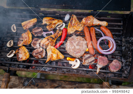 Assorted delicious grilled meat with vegetables over the coals on a barbecue 99849842