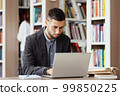 Man using laptop for research in library 99850225