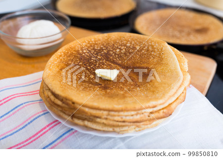 process of baking pancakes in pans on kitchen stove. stack of hot pancakes 99850810