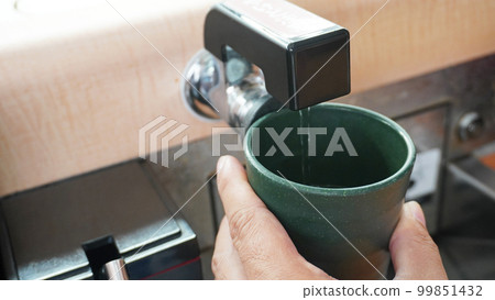 Pour hot water into the tea cup with the hot water supply lever at the conveyor belt sushi 99851432