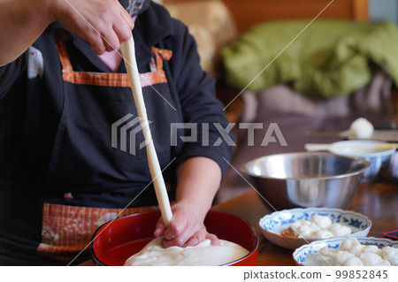 一位女士將配料與新鮮搗碎的麻糬混合 99852845