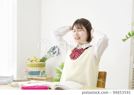High school girl holding her head while studying at home High school girl holding her head while studying at home 99853591