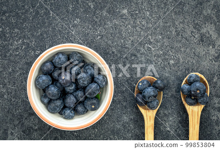 Blueberries on a textured black background, top view. 99853804