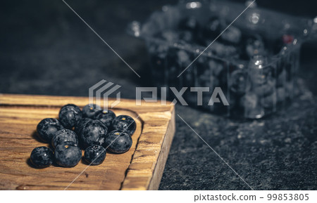 Blueberry berries close-up on a dark blurred background. Blueberry berries close-up on a dark blurred background. 99853805