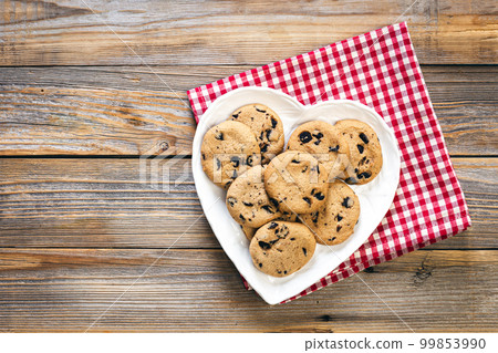 Heart shaped plate with chocolate chip cookies on wooden background, flat lay. Heart shaped plate with chocolate chip cookies on wooden background, flat lay. 99853990