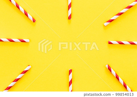 Party drinking straws arranged into a circle on yellow background. 99854013
