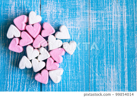 Pink and white marshmallows in the form of hearts on blue background, top view. Pink and white marshmallows in the form of hearts on blue background, top view. 99854014