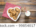 Plate with cookies, and a glass of milk on a wooden background, flat lay. 99854017