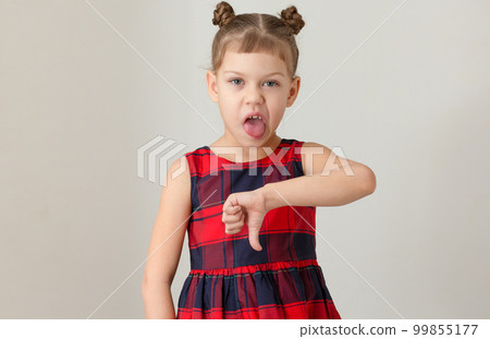 Child giving thumb down with funny face expressing disgust with open mouth and showing tongue caucasian 6 7 years in red plaid dress Child giving thumb down with funny face expressing disgust with open mouth and showing tongue caucasian 6 7 years in red plaid dress 99855177