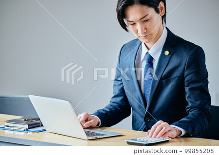 Young lawyer doing calculations on a calculator 99855208