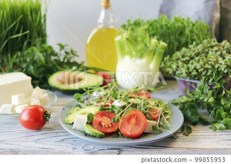 Salad of microgreens, avocado, tomatoes, cheese and arugula, on a plate, against the background of fennel and greens, recipe from natural ingredients, healthy food Salad of microgreens, avocado, tomatoes, cheese and arugula, on a plate, against the background of fennel and greens, recipe from natural ingredients, healthy food 99855953