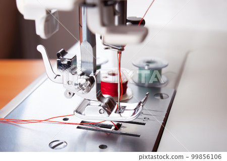 Modern sewing machine presser foot with red thread close up 99856106