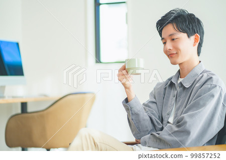 Young man relaxing on sofa with coffee 99857252