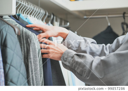 Young man organizing clothes in closet 99857286