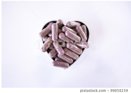 Pink capsules with supplements on a white background in the shape of a heart. Tablets and medications 99858239