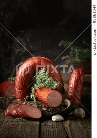 Smoked sausage with thyme and garlic on a wooden table. 99861044